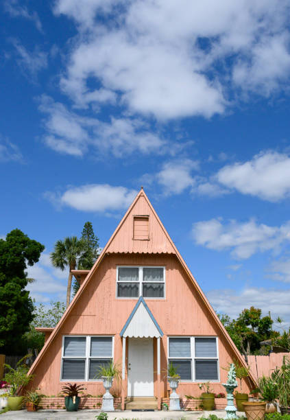 Chalet style triangle house painted a muted pink against a bright blue sky. Interesting architecture