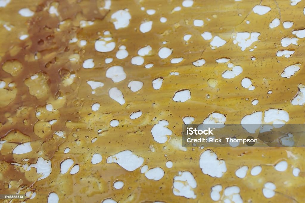 Marijuana concentrates: shatter 1 A form of concentrated marijuana called 'shatter.' When dried, this substance is brittle and easily shatters into tiny shards or flakes. After being heated the concentrate is spread out on parchment paper to cool. This shatter has cooled, which contracts the liquid, creating the holes in the poured material. Broken Stock Photo