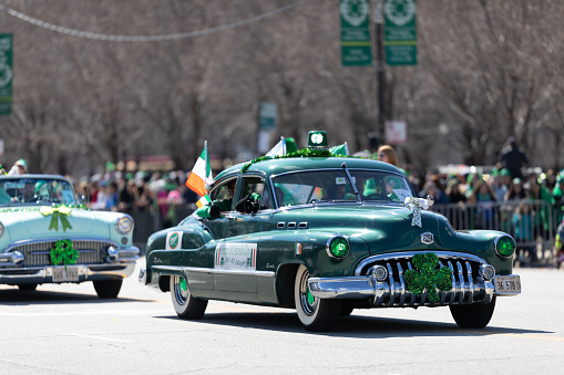 Chicago, Illinois, USA - March 16, 2019: St. Patrick's Day Parade, Buick Special, classic car, color green, with irish flags going down Columbus Drive