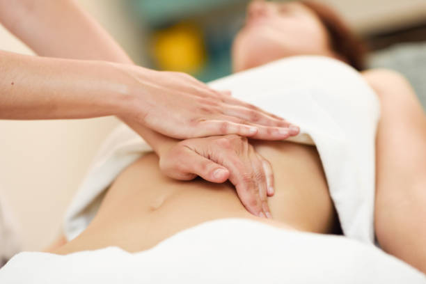 Therapist applying pressure on belly. Hands massaging woman abdomen. stock photo