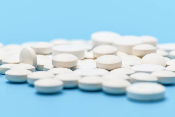 青の背景に白い丸い錠剤の多くのクローズアップ。医学的背景 - pill medicine laboratory narcotic ストックフォトと画像