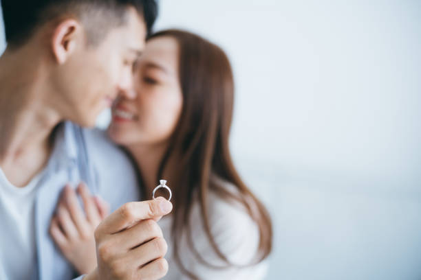человек с обруча кольцом предлагая брак с подругой в новом доме, они целуются с улыбкой - eternal city стоковые фото и изображения