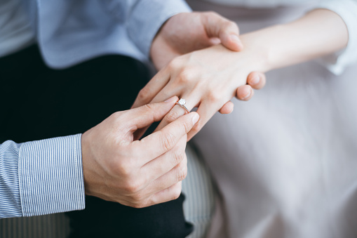 Cropped shot of a man putting an engagement ring onto his girlfriend's finger