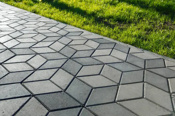 The footpath in the park is paved with diamond shaped concrete tiles.