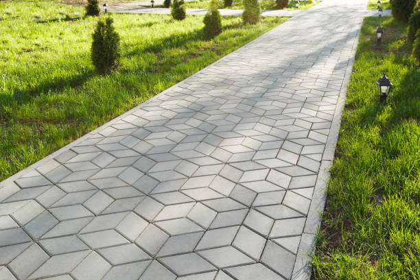 The footpath in the park is paved with diamond shaped concrete tiles. On the lawn - small decorative lights. stock photo