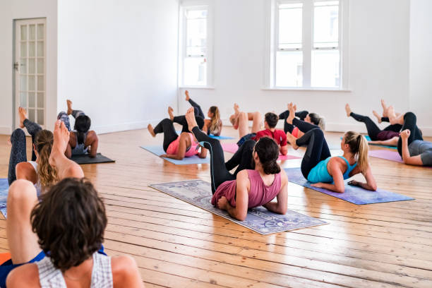 étudiants pratiquant le yoga dans la classe de formation de gymnastique - yoga class caucasian young adult group of people photos et images de collection