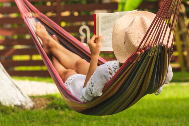 istock Attractive sexy woman reading book in hammock. 1145393326