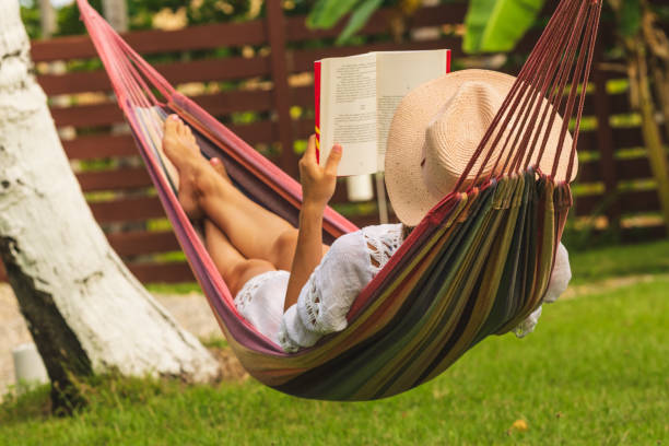 istock Attractive sexy woman reading book in hammock. 1145393485