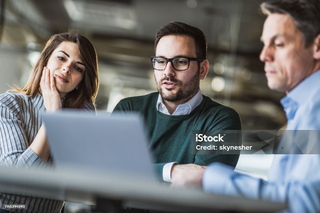 Junges Ehepaar und Immobilienmakler mit Laptop auf einem Treffen im Büro. - Lizenzfrei Rat Stock-Foto