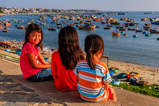 Vietnamese children looking at fishermen's boats  in a harbour, Vietnam