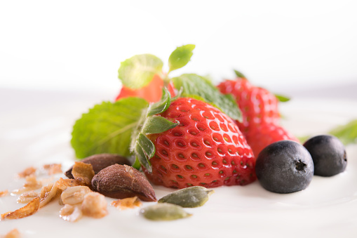 Plain yogurt with fresh berry fruits on top isolated on white background