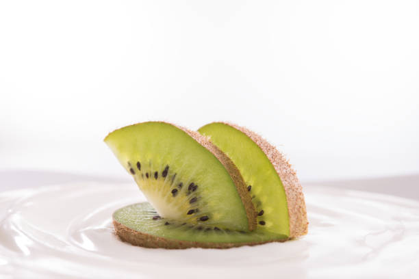 Plain yogurt with fresh kiwi fruit on top in bowl isolated on white background