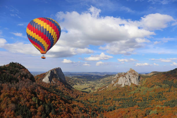 Hot air balloon flying over volcano. Auvergne, France Hot air balloon flying over ancient volcanos area. Tuiliere and sanadoire rocks. Monts dore, Auvergne, France auvergne rhône alpes photos stock pictures, royalty-free photos & images