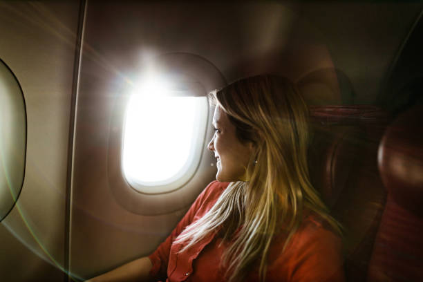 istock Young happy woman looking through window during her flight by plane. 1145409262