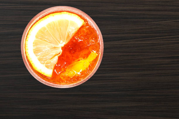 Ice black tea with lemon slice isolated on wooden table background.