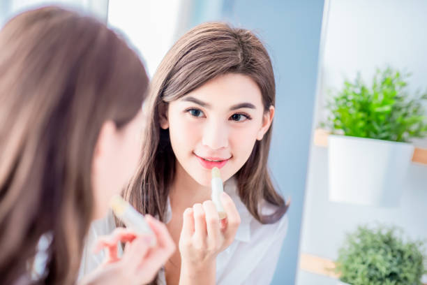 woman applying lip balm stock photo