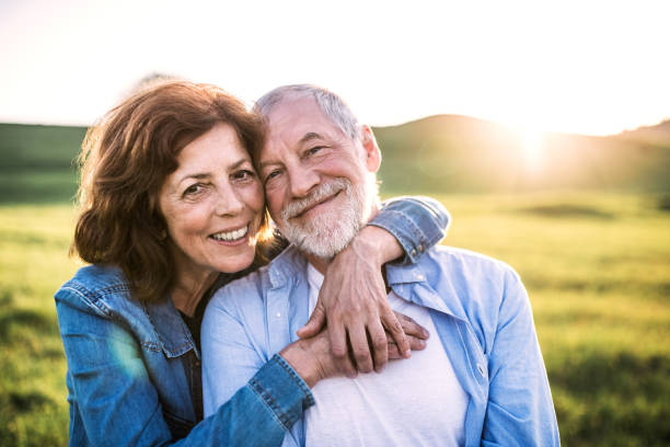 pareja de ancianos en la naturaleza primaveral al atardecer. - on top of grass scenics field fotografías e imágenes de stock