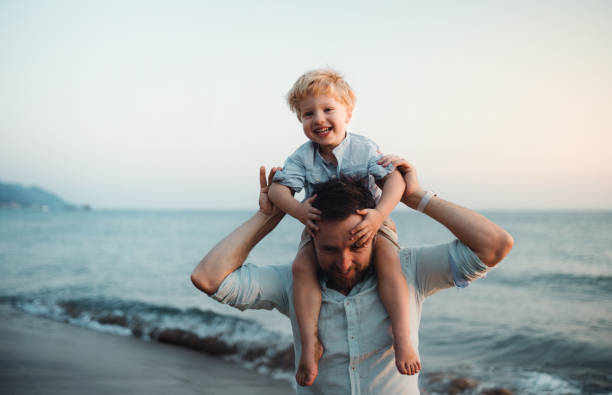 istock Father with a toddler boy standing on beach on summer holiday, having fun. 1145415836