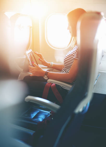 Female passenger of airplane working on tablet pc during fly stock photo
