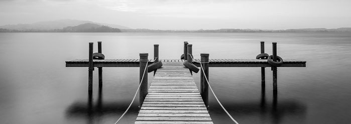 Wooden jetty on the lake in Black and white.  Clouds in the sky. Long Exposure. Switzerland.