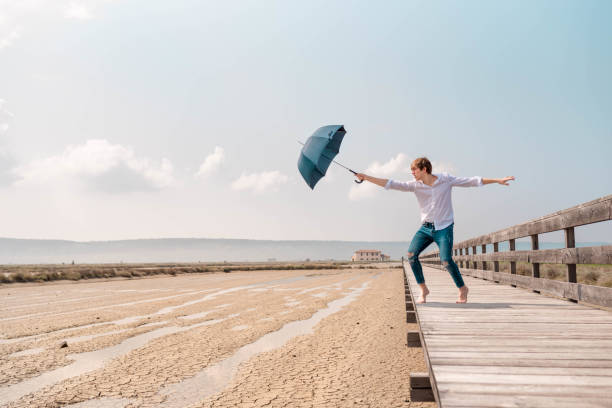 istock Young man holding un opened umbrella on a wooden pier 1145426028