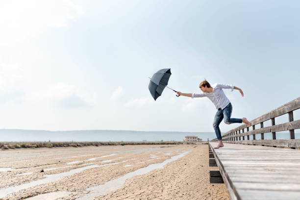 istock Young man holding un opened umbrella on a wooden pier 1145426034