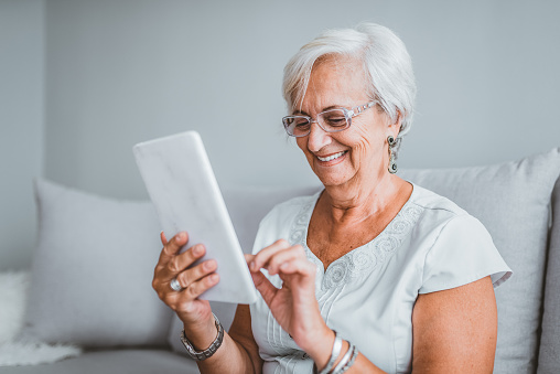 Mujer mayor feliz con computadora de Tablet PC en casa photo