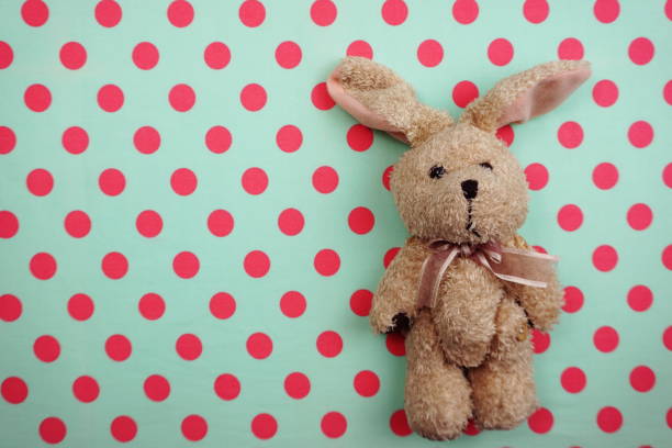 Cute rabbit doll Top view on pink and green polka dot background