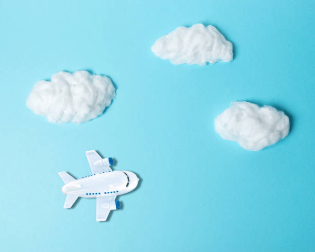 istock White cotton clouds with small airplane on pastel blue background. Minimal concept. 1145432390