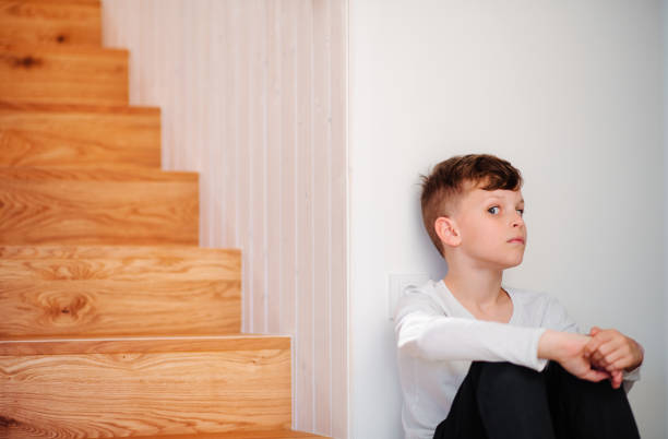 istock A small boy sitting on the floor by the stairs. Copy space. 1145433457