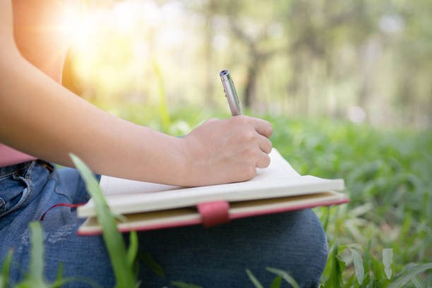 istock poem, poetry and knowledge education concept,  close up sitting writing on notebook in park 1145438829