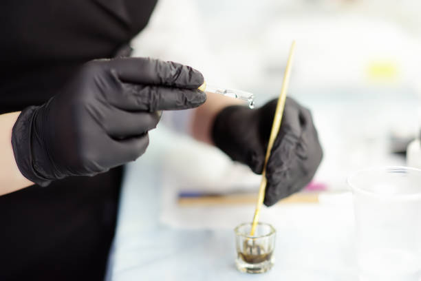 l'estetista agita il colore per le sopracciglia e lo prepara per l'uso. cura del viso e trucco in un salone professionale. - scrub brush immagine foto e immagini stock