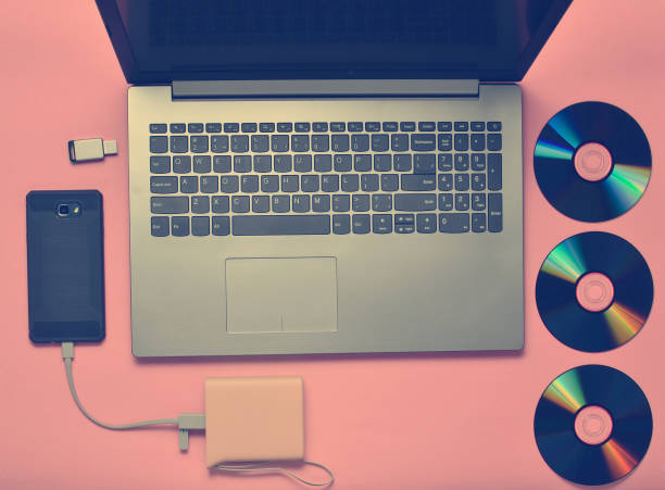 istock Laptop, smartphone, power bank, CD drives, USB flash drive on a pink background. Modern and outdated digital media and gadgets. 1145446582
