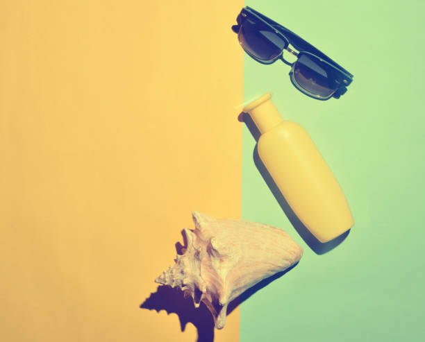 istock Sunglasses, sunblock, shell on a blue yellow background. Summer beach resort. Top view. 1145448894