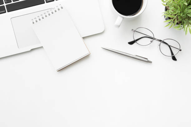 istock White office desk table with blank small notebook, laptop computer and supplies. Top view with copy space, flat lay. 1145452105