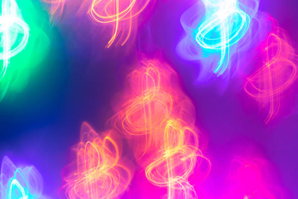 Multicolored neon glowing treble clefs on bright purple background as baskdrop or wallpapers. Abstract  luminous background. Photographic effect of long exposure.
