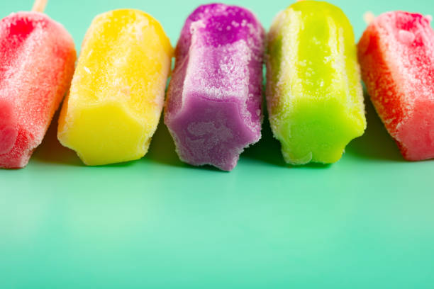 multi-color popsicles line up on green background with copy space