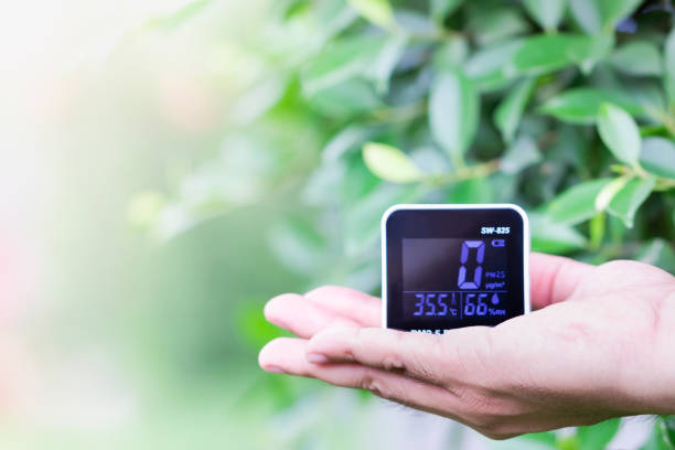 istock People hand holding PM 2.5 detector checking dust on blurred green leaf. 1145456812