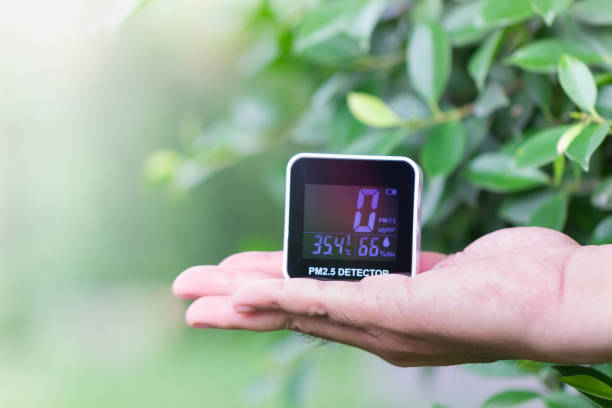 istock People hand holding PM 2.5 detector checking dust on blurred green leaf. 1145456821