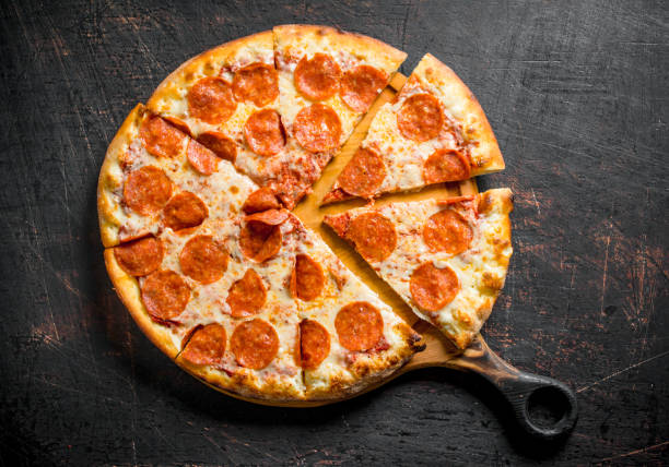 Crispy pepperoni pizza on the cutting Board. Crispy pepperoni pizza on the cutting Board. On dark rustic background pepperoni pizza stock pictures, royalty-free photos & images