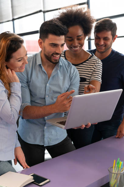 istock Professional diverse group of people at the office all looking at laptop's screen while talking and smiling 1145460954
