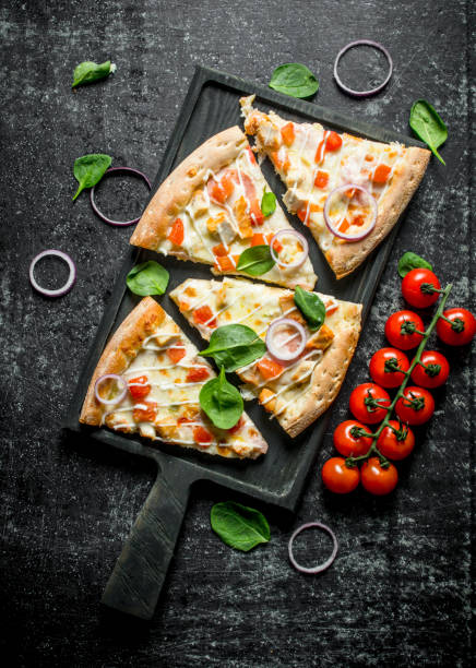 istock Slices of pizza with tomatoes on a branch and spinach. 1145461091