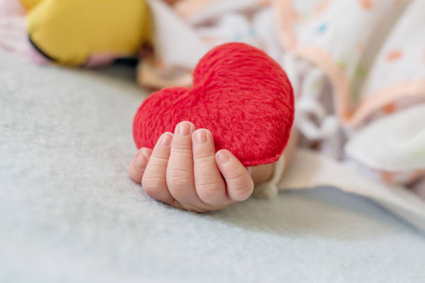 istock Baby's hand with a red heart 1145462188