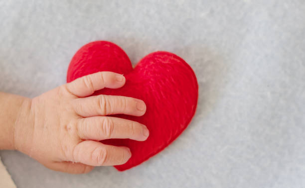 istock Baby's hand with a red heart 1145462215