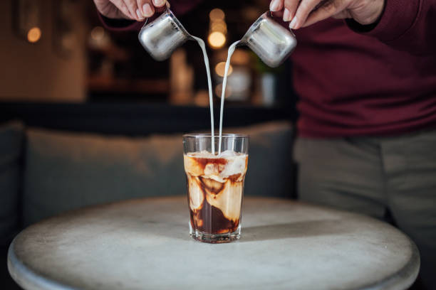 homme versant le lait dans le café glacé - pouring coffee human hand cup photos et images de collection