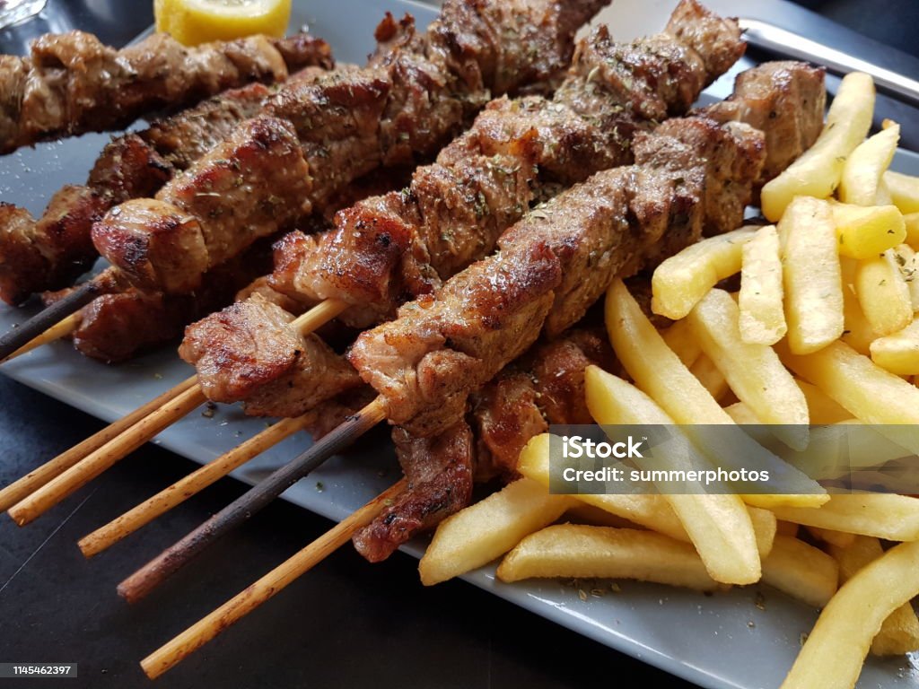 souvlaki greek etnic food mear roasted in a plate wiht lemon and potatoes Chicken Meat Stock Photo