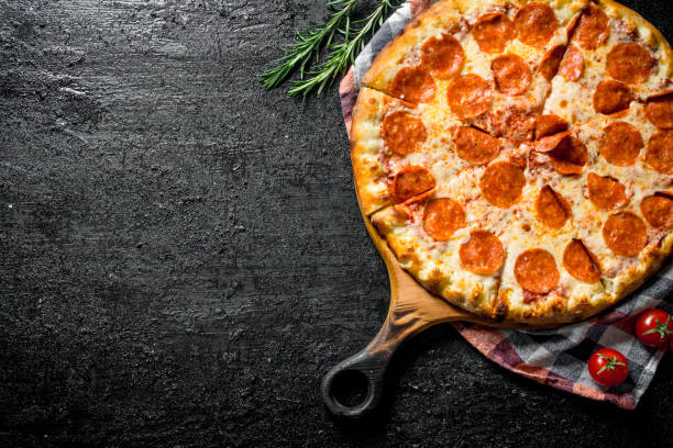 istock Sliced pepperoni pizza with rosemary and tomatoes. 1145462840