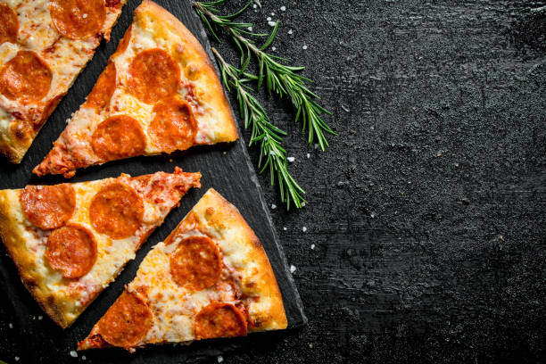 istock Slices of fragrant pepperoni pizza on a stone Board. 1145464879