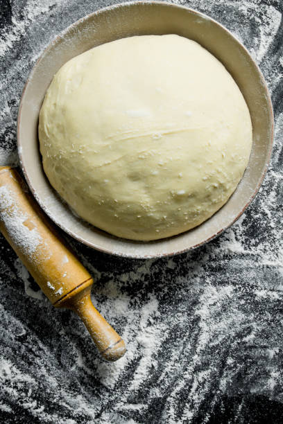 istock Flour background. The dough in a bowl with a rolling pin. 1145469205