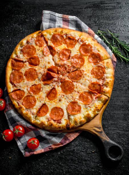 istock Sliced pepperoni pizza with rosemary and tomatoes. 1145471482